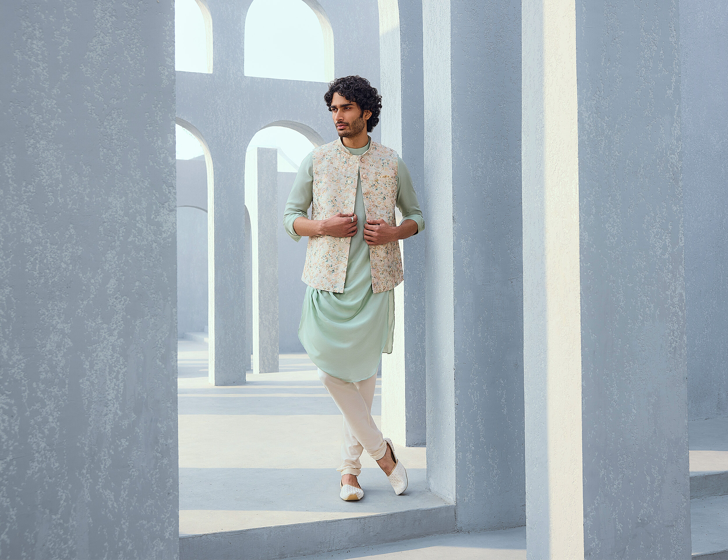 Man in an elegant white Nehru jacket paired with matching white juttis for a sophisticated wedding look.